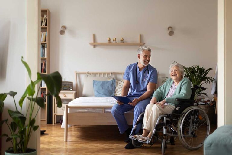 A middle-aged woman speaks with an older man in a cozy residential living room, both looking attentive and engaged.