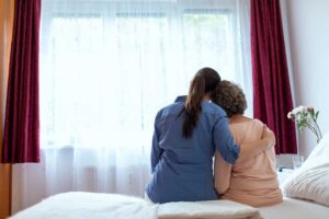 Older adult arranging labeled clothing and family photos in a bright assisted living room.