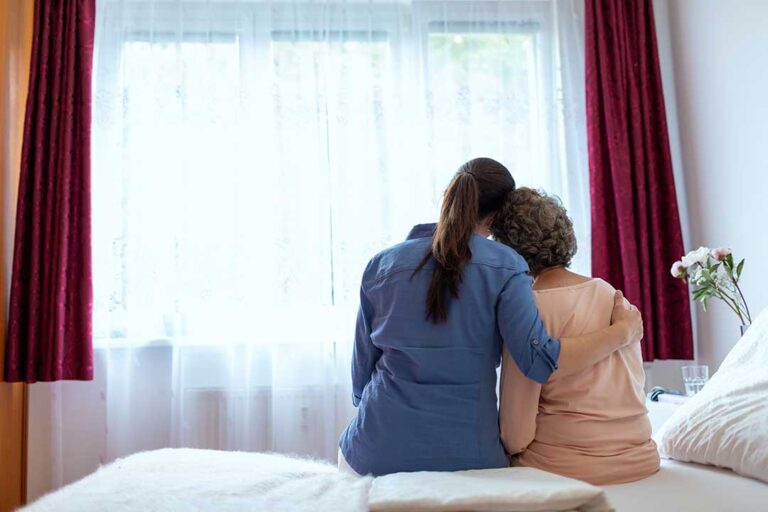 Older adult arranging labeled clothing and family photos in a bright assisted living room.